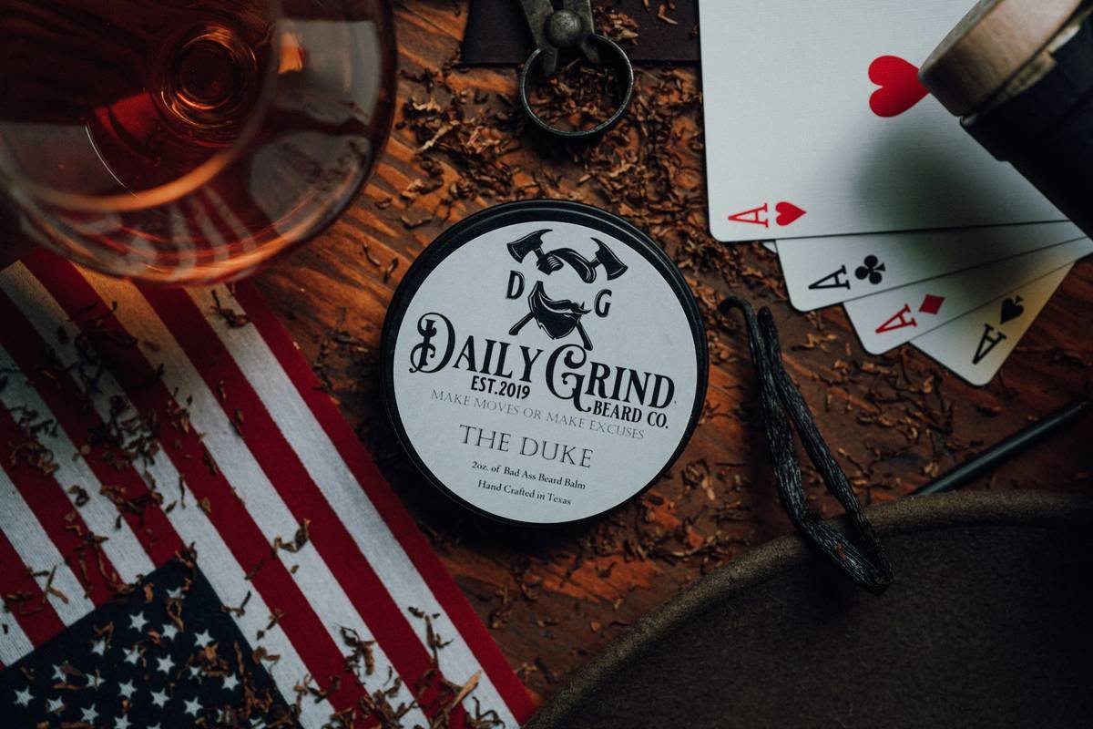 Product photo of The Duke Beard Balm by Daily Grind Beard Co. Product Photography by Lance Reis. I added elements of Rum, Tobacco, and Wood to visually showcase the scents you can expect with The Duke.